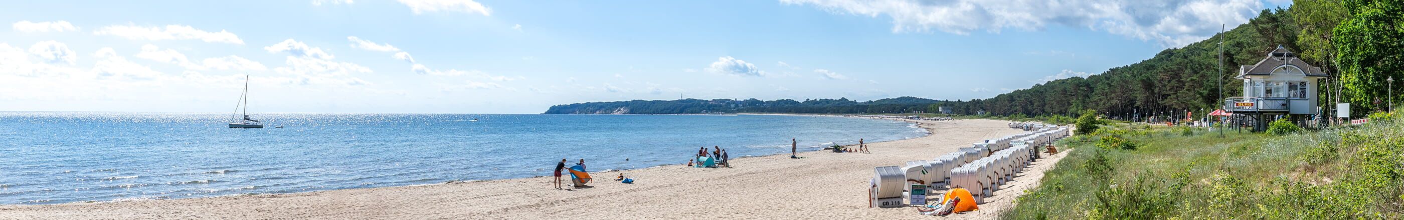 Ostseestrand mit Strandkörben, Segelboot und Badegästen