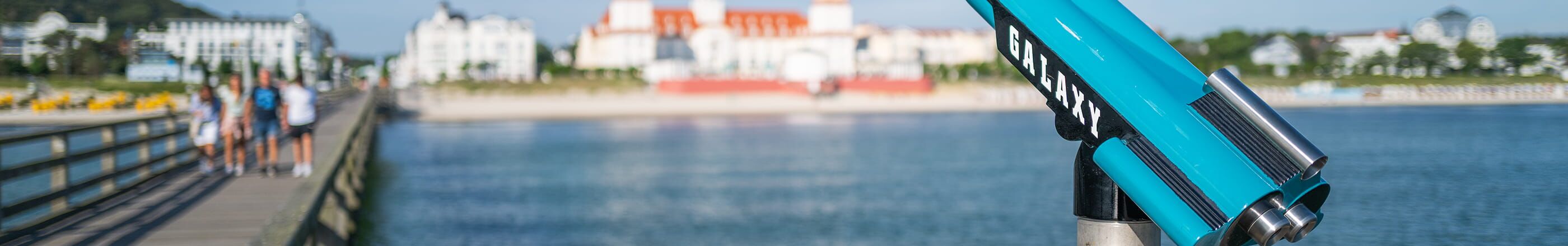Fernrohr auf der Seebrücke mit Blick auf Ostsee und Gebäude